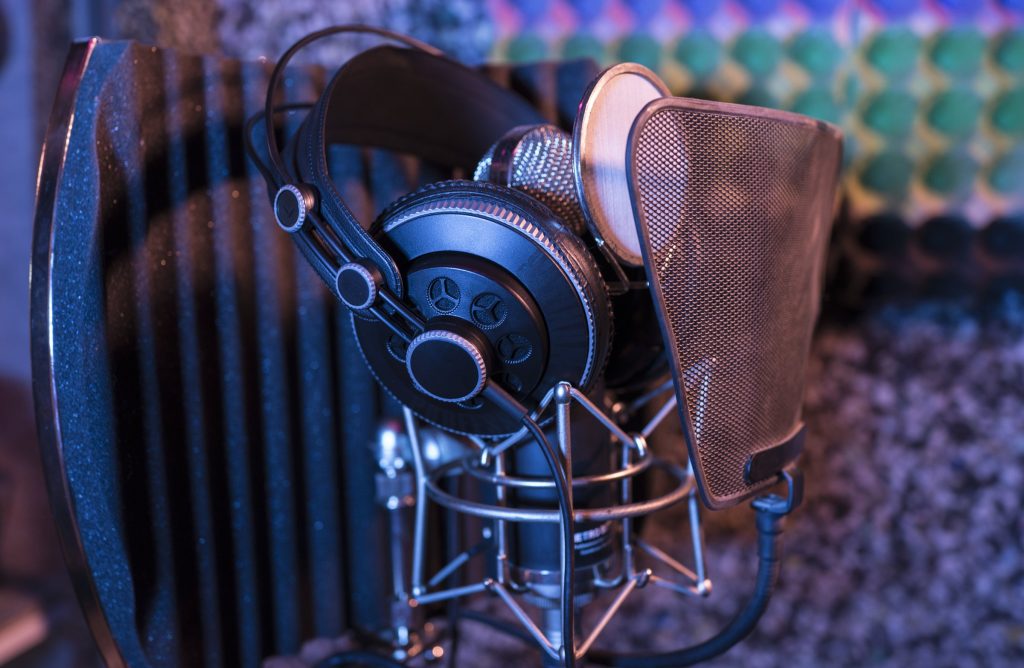 A microphone and headphones on a stand, lit warm