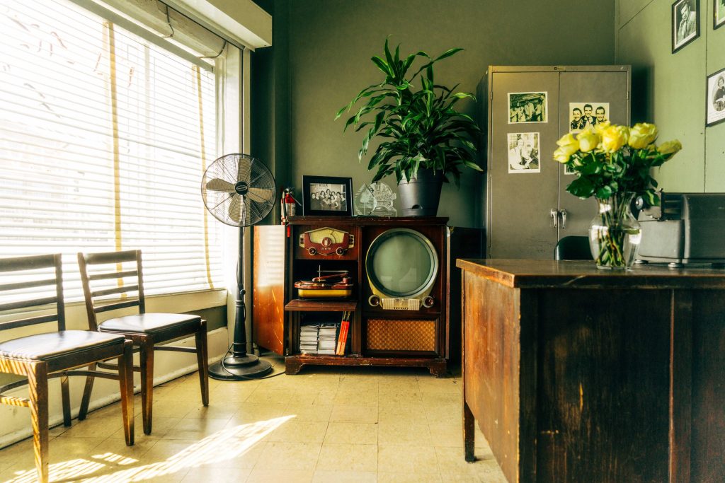 A quiet room with a vintage radio, plants and a fan
